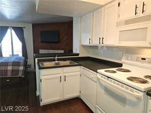 Kitchen featuring sink, white appliances, white cabinetry, backsplash, and dark hardwood / wood-style flooring