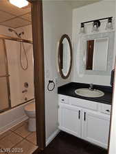 Full bathroom featuring toilet, vanity, shower / bath combination with glass door, and tile patterned flooring