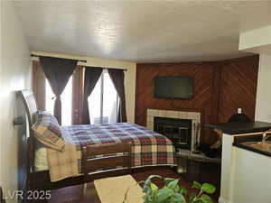 Bedroom featuring wooden walls, a textured ceiling, and a fireplace