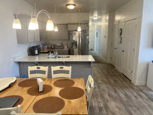 Kitchen with stainless steel refrigerator with ice dispenser, sink, decorative light fixtures, dark hardwood / wood-style floors, and gray cabinets