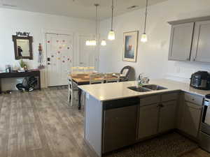 Kitchen with sink, hanging light fixtures, kitchen peninsula, hardwood / wood-style flooring, and stainless steel appliances