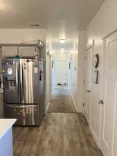 Interior space featuring stainless steel refrigerator with ice dispenser, dark hardwood / wood-style floors, and a textured ceiling