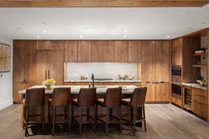 Kitchen featuring light stone counters, a kitchen island with sink, and light hardwood / wood-style flooring