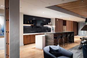 Bar featuring tasteful backsplash, sink, and light hardwood / wood-style flooring