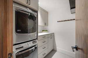 Washroom featuring cabinets and stacked washer / dryer