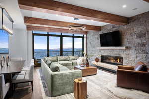 Living room featuring hardwood / wood-style flooring, floor to ceiling windows, a fireplace, and beam ceiling