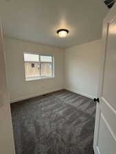 Spare room featuring dark carpet and a textured ceiling