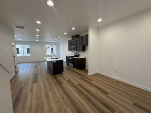 Kitchen with sink, dark wood-type flooring, stainless steel appliances, and a center island with sink