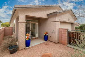 Back of house with a garage, fence, and stucco siding