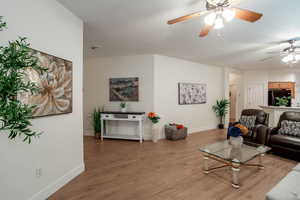 Living area with a textured ceiling, wood finished floors, a ceiling fan, and baseboards