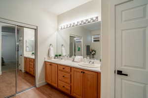 Full bath with double vanity, wood finished floors, a sink, and baseboards