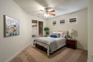 Bedroom with a ceiling fan, light colored carpet, and baseboards