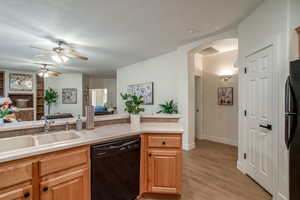 Kitchen with arched walkways, a sink, open floor plan, light countertops, and black appliances