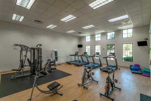 Workout area featuring visible vents, a towering ceiling, a drop ceiling, and wood finished floors