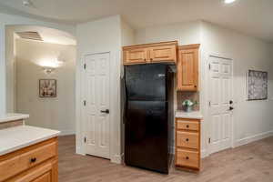 Kitchen with freestanding refrigerator, visible vents, light countertops, and arched walkways