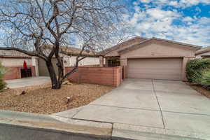 Ranch-style home featuring a garage, driveway, fence, and stucco siding