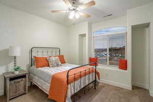 Carpeted bedroom featuring a ceiling fan, visible vents, and baseboards