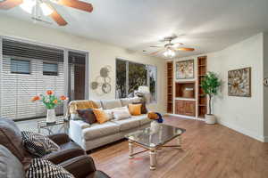 Living area featuring baseboards, visible vents, a ceiling fan, a textured ceiling, and light wood-type flooring