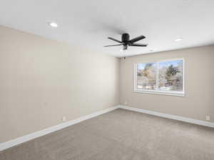 Carpeted spare room with ceiling fan and a textured ceiling