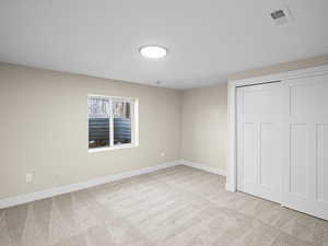 Unfurnished bedroom featuring light colored carpet and a closet