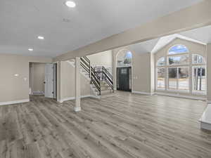 Interior space with lofted ceiling, light hardwood / wood-style floors, and a textured ceiling