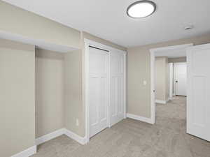 Unfurnished bedroom with light colored carpet and a closet