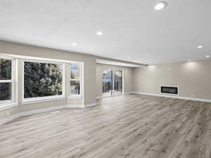 Unfurnished living room with light hardwood / wood-style flooring and a textured ceiling
