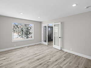 Unfurnished room with french doors, a textured ceiling, and light wood-type flooring