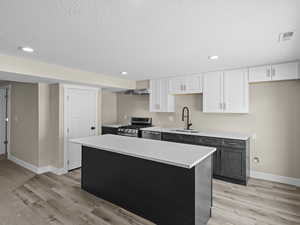 Kitchen featuring a kitchen island, appliances with stainless steel finishes, sink, and white cabinets