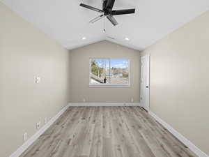 Empty room with ceiling fan, lofted ceiling, and light wood-type flooring