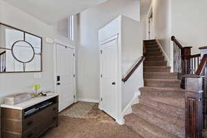 Entrance foyer featuring carpet and vaulted ceilings