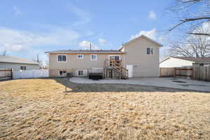 Back of property featuring a yard, a patio area, entrances to lower level and garage,