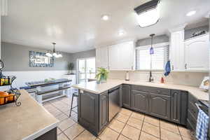 Kitchen featuring white cabinetry, sink, stainless steel dishwasher, and kitchen peninsula