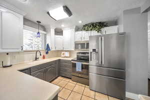 Kitchen with sink, gray cabinetry, hanging light fixtures, stainless steel appliances, and white cabinets