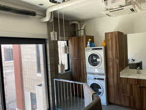 Clothes washing area featuring stacked washer / dryer and sink