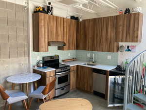 Kitchen featuring sink, decorative backsplash, beverage cooler, and appliances with stainless steel finishes