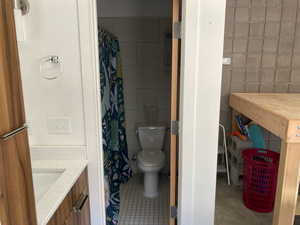 Bathroom with tile patterned flooring, vanity, tile walls, and toilet