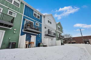 Snow covered rear of property featuring central air condition unit