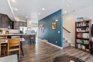 Kitchen featuring dark brown cabinetry, a kitchen bar, appliances with stainless steel finishes, dark hardwood / wood-style flooring, and kitchen peninsula