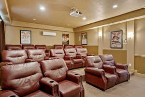 Home theater room with light carpet and a wall mounted air conditioner