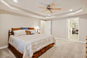 Carpeted bedroom with a tray ceiling and ceiling fan