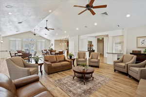 Living room with vaulted ceiling, a textured ceiling, and light wood-type flooring