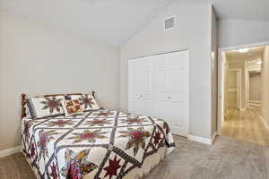 Carpeted bedroom featuring lofted ceiling and a closet