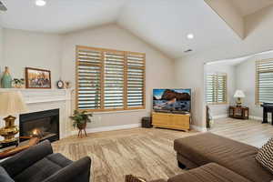 Living room with lofted ceiling, hardwood / wood-style floors, and a fireplace