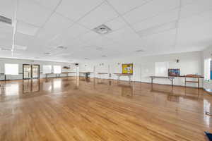 Workout room with light hardwood / wood-style flooring and a drop ceiling