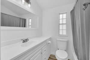 Bathroom with vanity, lofted ceiling, a wealth of natural light, and toilet