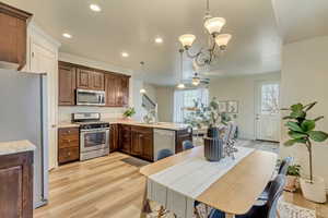 Kitchen featuring new LVP flooring, crown molding, stainless steel appliances, kitchen bar, and pendant lighting