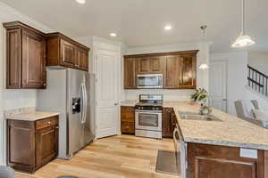 Kitchen featuring new LVP flooring, crown molding, stainless steel appliances, kitchen bar, and pendant lighting