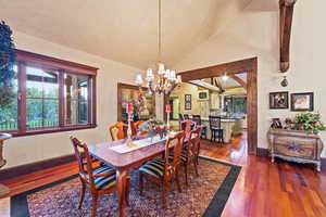 Dining space featuring dark wood-type flooring, a chandelier, and high vaulted ceiling