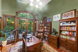 Office space featuring an inviting chandelier, hardwood / wood-style flooring, french doors, and a towering ceiling